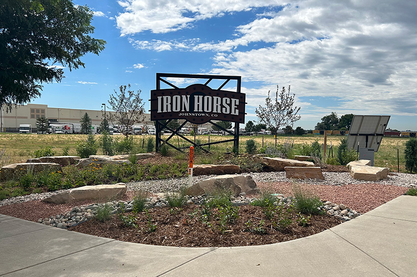 Sign reading “Iron Horse Johnstown, CO” stands in a landscaped area with rocks and plants, under a partly cloudy sky. Sign reading "Iron Horse Johnstown, CO" stands in a landscaped area with rocks and plants, under a partly cloudy sky.